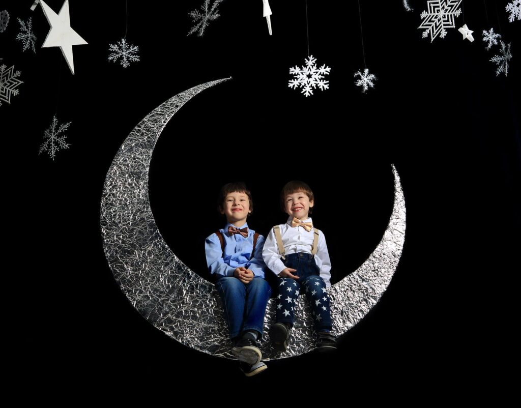 two boys sitting on crescent moon
